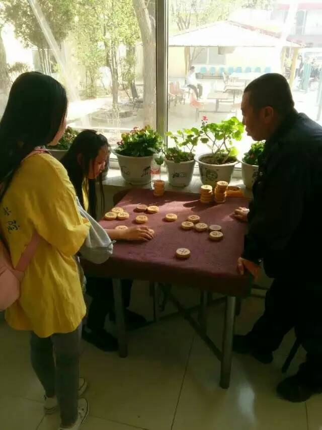 呼和浩特职业学院团委开展“送温暖进人心，关怀无处不在，温暖传递爱心永驻”主题公益活动：志愿者陪老人下棋.jpg